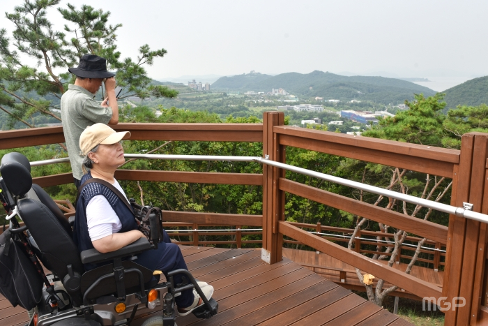 이번 숲길 조성으로 정상에 처음 올라온 휠체어 장애인이 북한을 바라보고 있다.