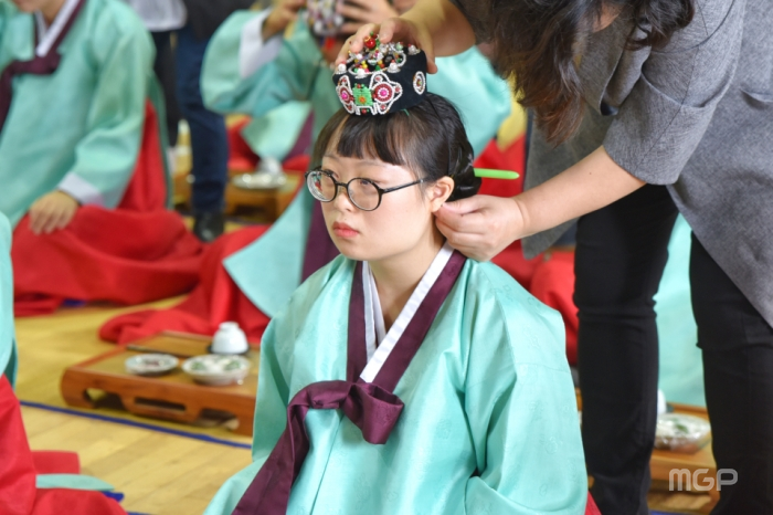 성년례에 참여하는 학생 머리 위에 족두리를 올리고 있다.