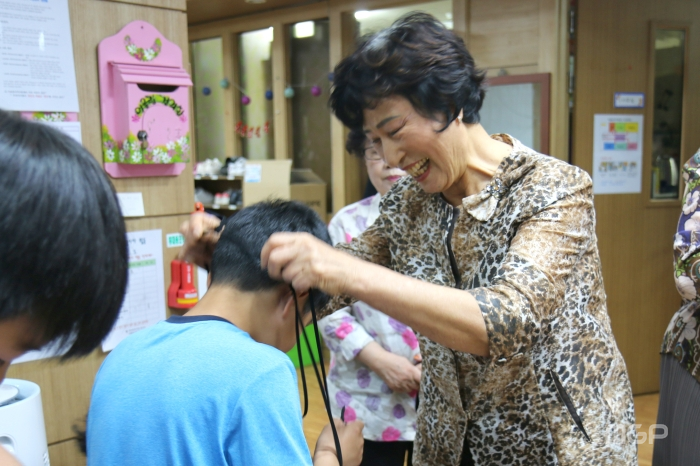 자원봉사자가 카드지갑목걸이를 지역아동센터 어린이에게 전달하고 있다.