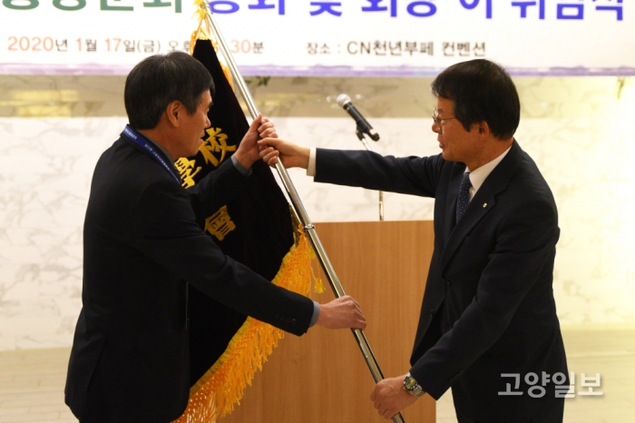 김진의 전임 회장이 김진용 신임 회장에게 총동문회 깃발을 전달하고 있다.