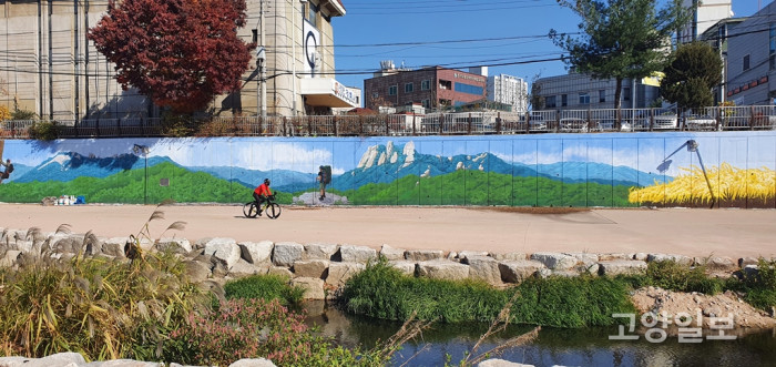 백석천의 대형 벽화 옆으로 한 시민이 자전거를 타고 지나가고 있다.